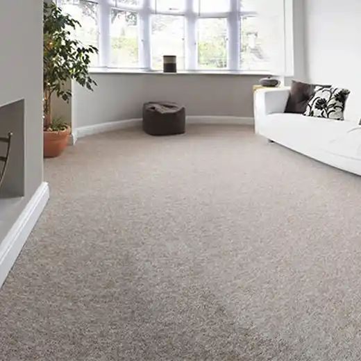 A spacious, open-plan room with dark grey carpeting, modern furniture, and large windows in the background.